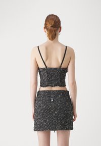 Set crop top e gonnellino mini in tweed bianco e nero con spalline sottili, orli frangiati e un'etichetta sul retro della gonna. Design testurizzato e aderente.