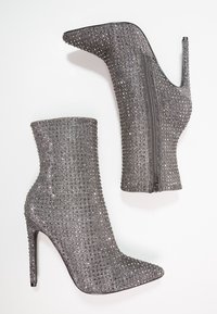 Bottines grises à talons hauts en matière texturée, ornées de petits strass et dotées d'une fermeture éclair sur un côté.