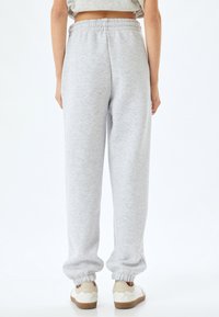 Grijze joggerbroek met een elastische tailleband, aansluitende enkels en een zachte textuur. Gemaakt met witte sneakers met beige accenten.