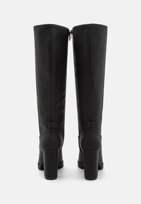 Stivali neri alti fino al ginocchio con finitura in pelle liscia, tacco spesso e cerniera posteriore. Presentano una forma solida e strutturata con accenti minimalisti.