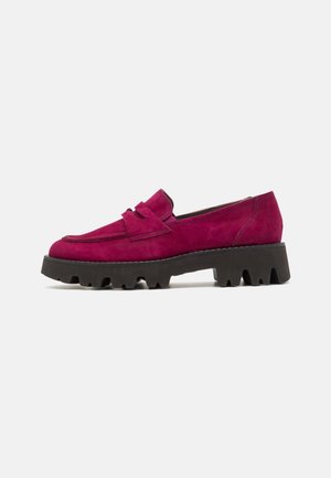 Mocassin en daim rose foncé pour femme avec semelle noire à gros crampons et bride décorative sur le cou-de-pied, montré de profil.