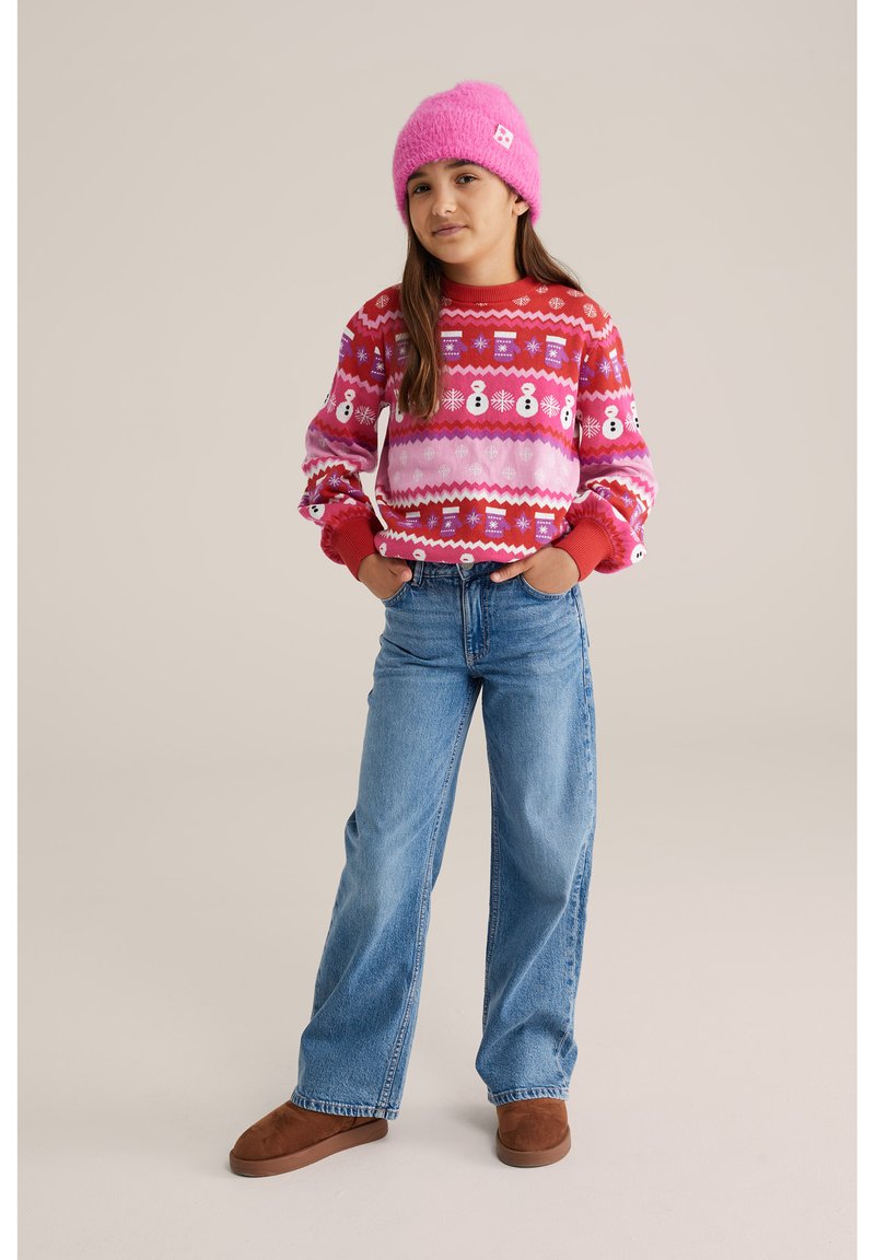 Sarkans un rozā rakstains džemperis ar sniegavīriem, džinsa bikses un brūni zamšādas zābaki, pārklāti ar mīkstu rozā adītu beanie cepuri.
