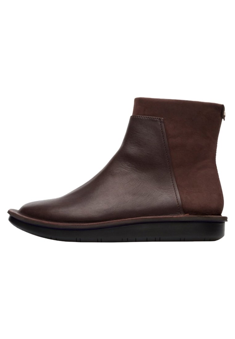 Botas tobilleras de cuero marrón con un acabado liso y paneles laterales de ante. Suela de goma negra baja con una ligera curvatura hacia arriba en la punta.