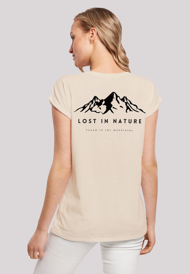 Beige cotton t-shirt with short rolled sleeves. Black mountain graphic on the back features the text "LOST IN NATURE" and "found in the mountains."