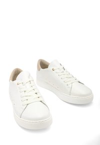 Weiße Leder-Sneaker mit runder Zehenpartie, flachen Gummisohlen, geschnürtem Design und beigen Akzenten an Ferse und Zunge. Dezente Perforationsdetails.