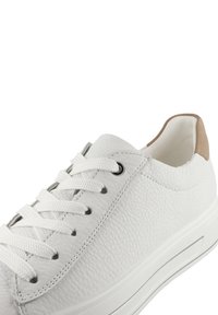 Vita lädersneakers med texturerad yta, rund tå och vita snören. Anmärkningsvärd tan läderdetalj vid hälen. Platt gummisula.