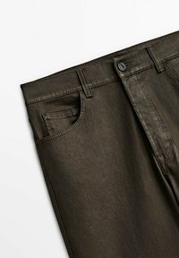 Pantalon vert olive foncé avec poche avant, passants pour ceinture et fermeture par bouton sur fond blanc.