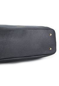 Unteransicht einer schwarzen, strukturierten Ledertasche mit goldenen Füßen und einem teilweisen "VENEZIA"-Logo in goldener Schrift.