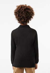 Black pullover with a collar, long sleeves, and a textured fabric. Features a standard fit and a smooth surface. No visible patterns or accents.