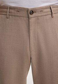 Beige op maat gemaakte broek van gestructureerde stof, met een rits aan de voorkant, knoopsluiting en zijzakken met een gladde afwerking.