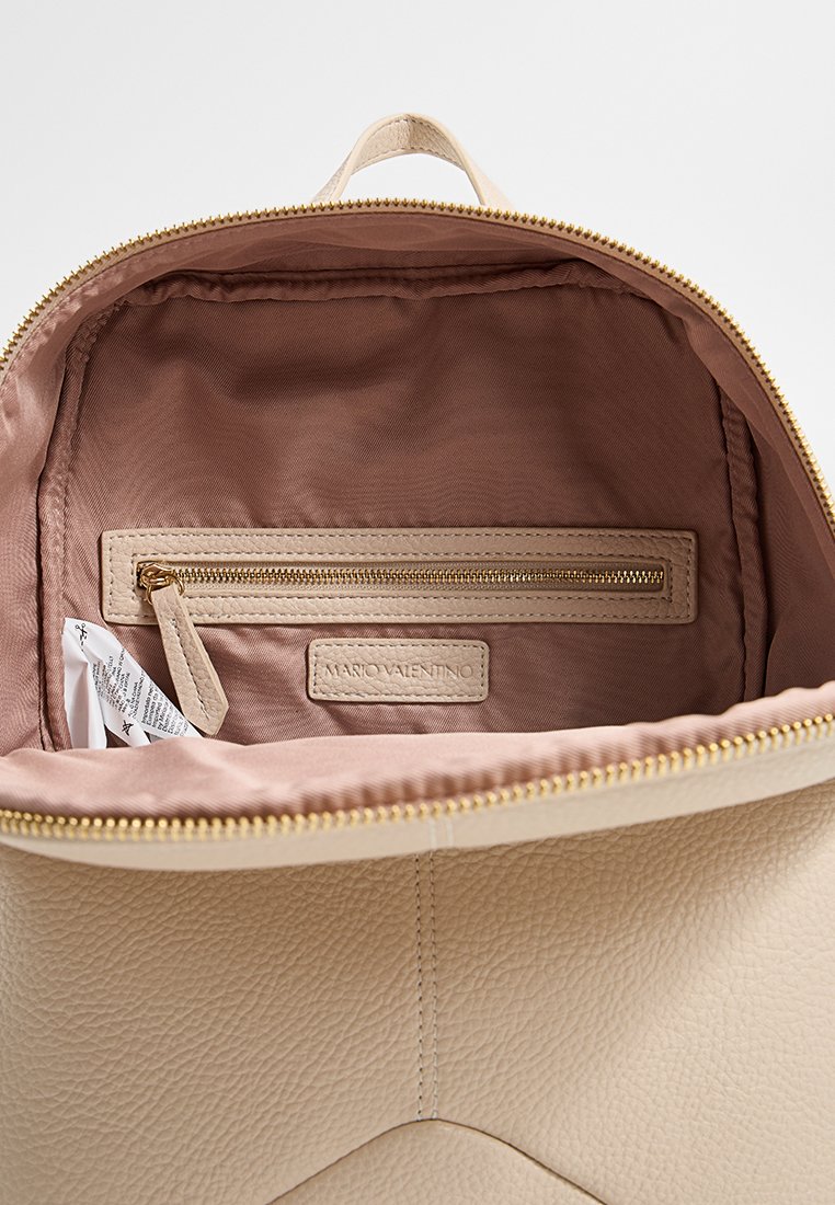 Beiger Leder-Rucksack Innenraum mit glattem, pinkfarbenem Futter, Reißverschlusstasche, Logo-Patch und goldfarbenen Reißverschluss-Details.