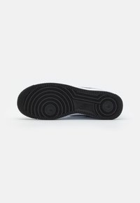 Nike sneaker talpa fekete gumiból készült, körkörös taposómintázattal, sima, lapos kialakítással és dombornyomott logó részlettel.