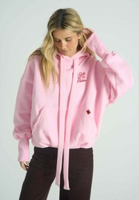 Růžová oversized mikina z měkké látky, s přední kapsou, šňůrkami a červeným nápisem "Girls Go To Pilates."