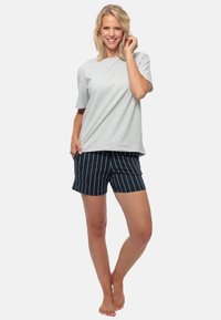 Grijze T-shirt met korte mouwen, gecombineerd met marineblauwe streepjesshorts. De stof lijkt zacht, met een ontspannen pasvorm en een eenvoudig ontwerp. Geen opvallende hardware.