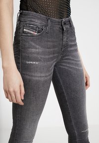 Vaqueros de denim gris de cintura alta con un ligero diseño deshilachado, bolsillos frontales y una pequeña etiqueta de la marca en la cinturilla.
