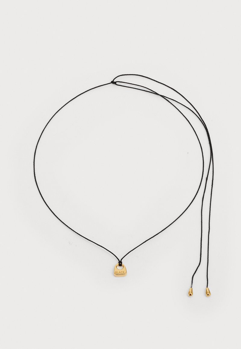 Collar de cordón negro con un colgante en tono dorado con la inscripción "BLACK". El diseño incluye dos extremos ajustables con puntas metálicas.