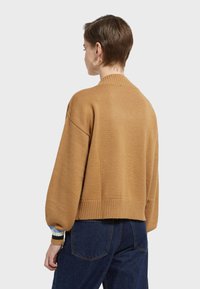 Brauner gestrickter Pullover mit einem verkürzten Design, geripptem Saum und Ballonärmeln mit kontrastierenden gestreiften Bündchen. Glatte Textur.