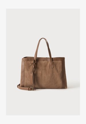 Sac cabas en daim et cuir marron avec doubles poignées, bandoulière détachable et détail pompon décoratif sur fond uni.