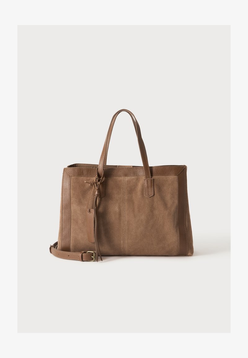 Sac cabas en daim et cuir marron avec doubles poignées, bandoulière détachable et détail pompon décoratif sur fond uni.