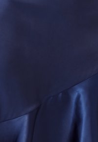 Tessuto blu scuro con una trama opaca liscia sovrapposto a un materiale di raso lucido, pieghe visibili e dettagli di caduta morbida.