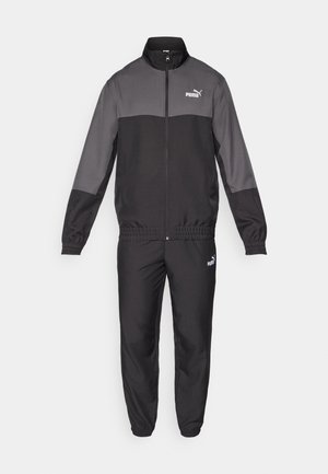 De Puma trainingsoutfit bevat een volledig ritssluiting jack met grijze en zwarte panelen en bijpassende broek. Gemaakt van een gladde stof met elastische manchetten en tailleband.