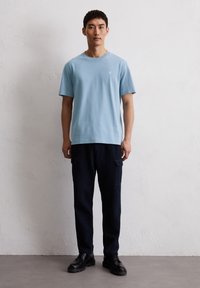 Light blue cotton t-shirt with a crew neckline, paired with dark navy cargo pants featuring side pockets and black lace-up shoes.