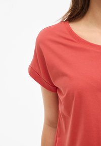 Koralfarvet t-shirt med en afslappet pasform, rund halsudskæring og opsmøgte korte ærmer. Fremstillet af blødt bomuldsstof med en glat tekstur.