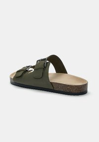 Infradito verde oliva con cinturini regolabili in metallo argentato, texture in suede, fodera in sughero e suola in gomma nera texturizzata.