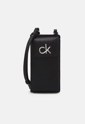 Bolso bandolera negro texturizado con correa ajustable, cierre de solapa y logo metálico "ck" en la parte delantera.