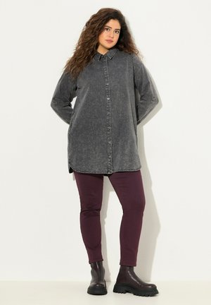 Pitkä, nappikiinnitteinen paita haalistuneesta mustasta denimmateriaalista, jossa on kauluspaita ja sivutaskut. Yhdistetty burgundinpunaisiin slim fit -housuihin ja mustiin nilkkureihin.