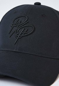 Gorra negra de algodón, con un logotipo bordado negro en relieve en la parte frontal y un visera curva. La superficie es lisa con costuras texturizadas.