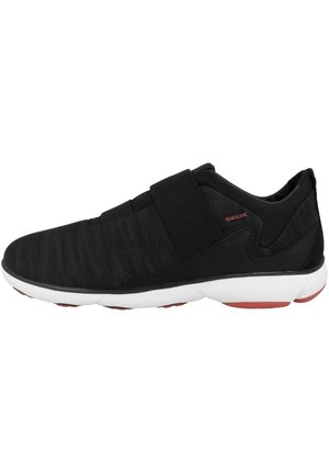 Scarpe da atletica nere con un upper in tessuto testurizzato, cinturino regolabile e intersuola bianca con accenti rossi sulla suola in gomma.