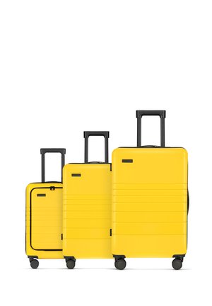 Three yellow hard-shell suitcases of varying sizes feature horizontal lines, black handles, and wheels for easy maneuverability.