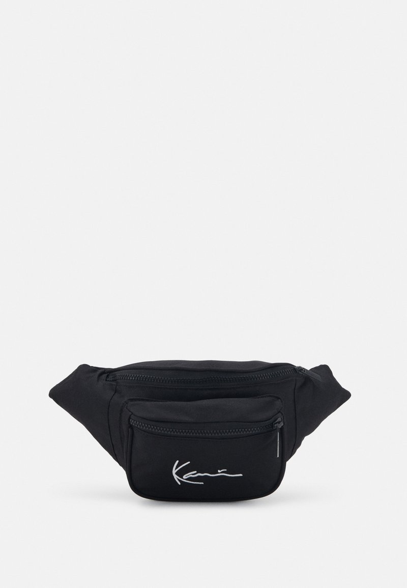 Riñonera de tela negra con dos bolsillos con cremallera. Presenta una textura suave y un logotipo bordado en blanco en el bolsillo frontal.