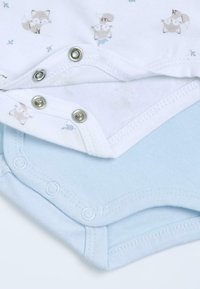 Deux bodies pour bébé, un blanc avec de petits motifs de renard et des boutons-pression métalliques, et un bleu clair uni avec des boutons-pression assortis.