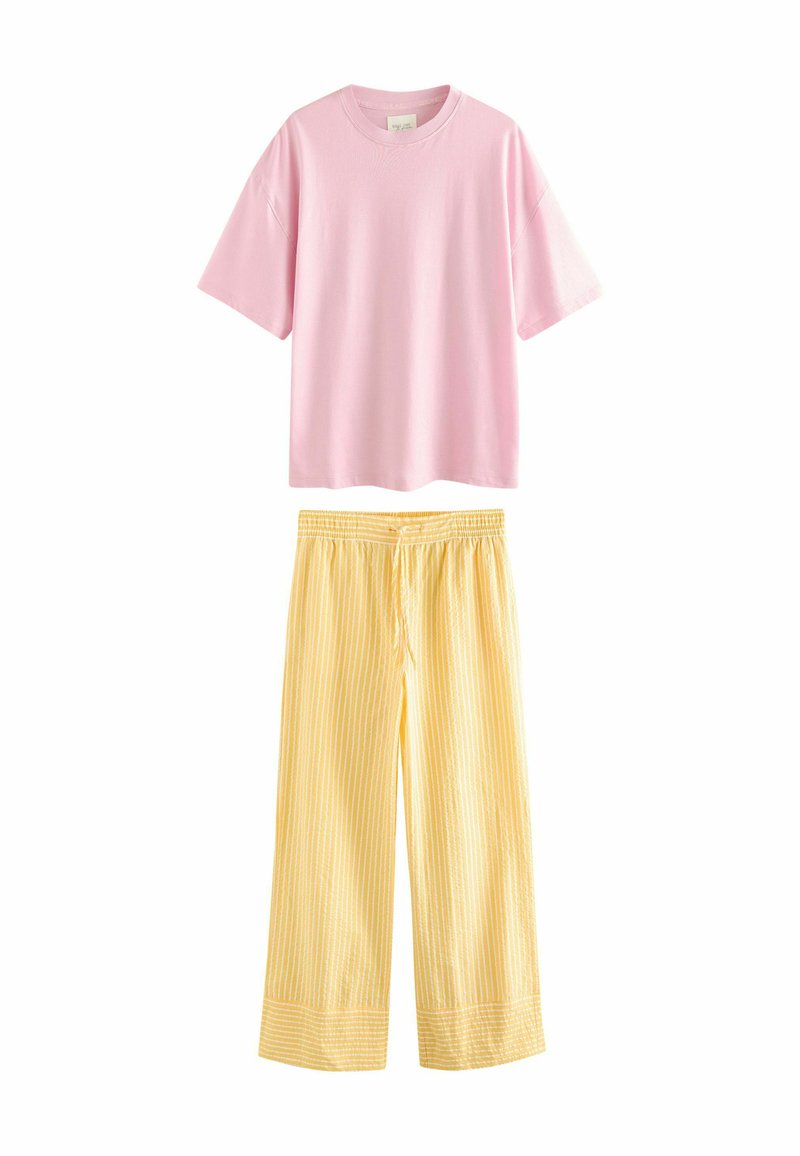 T-shirt rose à manches courtes sur un pantalon large à rayures jaunes avec taille élastique et cordon de serrage. Tissu doux, design décontracté.