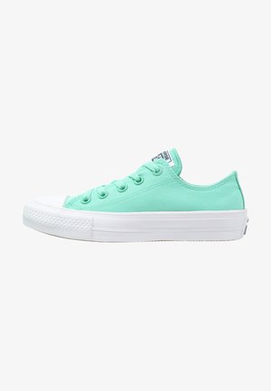 Baskets basses en toile vert clair avec semelle et bout en caoutchouc blanc, lacets verts assortis et logo sur la languette.