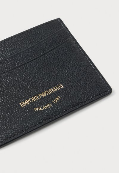 Μαύρος δερμάτινος θήκη κάρτας με υφή πέτρινου ανάγλυφου, πέντε θήκες για κάρτες και χρυσά ανάγλυφα γράμματα που αναγράφουν "EMPORIO ARMANI MILANO 1981."