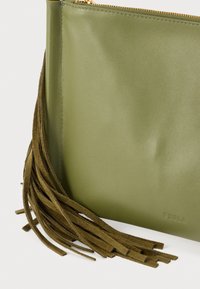 Zöld bőrből készült kis táska cipzáras záródással, hosszú, velúr bojtokkal díszítve, dombornyomott logóval, sima textúrával és strukturált formával.