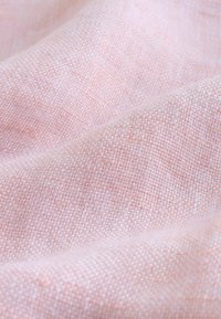  Lichtroze geweven stof met een gestructureerd, dicht gebreid patroon, met subtiele variaties in kleur en een zachte, gladde oppervlakte.