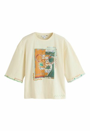 T-shirt i cremefarve med løs pasform og brede ærmer, der har en farverig grafik af en vase og en plante samt dekorativ zigzag-sømme på ærmer og kant.