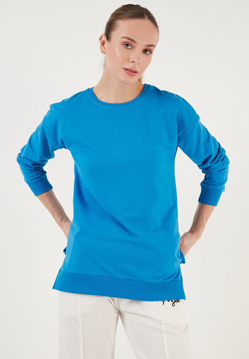Sudadera azul de manga larga, con cuello redondo, puños acanalados y dobladillo. Tejido suave con un corte relajado y detalles de abertura a los lados.