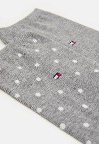 Calzini grigi con pois bianchi e un piccolo logo multicolore. Il materiale sembra morbido con una texture liscia. Design classico.