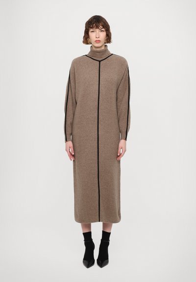 Long, brown-knit dress with a high collar, featuring black vertical seams and long, puffed sleeves, paired with black sock-like ankle boots.