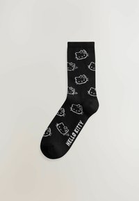 Zwarte sokken met een herhaalbaar witte Hello Kitty-afbeelding en de tekst "HELLO KITTY" op de boord. Gebreide stof, standaard crewlengte.