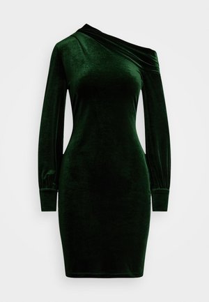 Zielona aksamitna sukienka z asymetrycznym dekoltem, długim rękawem i dopasowanym krojem. Gładka tekstura i detal w formie marszczonego mankietu.