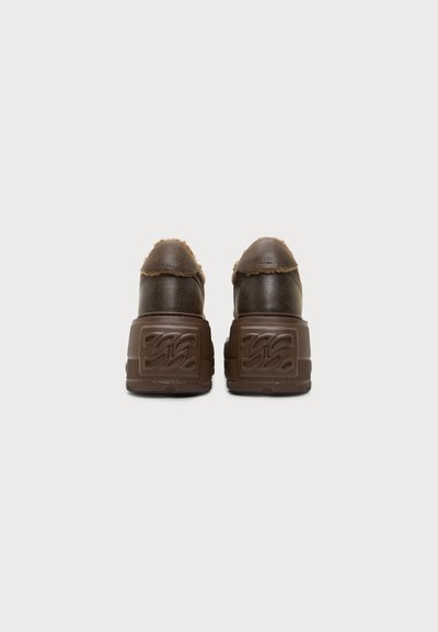 Paire de chaussures en cuir marron avec semelles épaisses à plateforme vues de dos sur un fond clair uni.