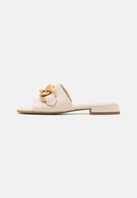 Beige platt sandaler med en bred rem, prydda med en stor guldkedja och fyrkantig klack. Slät läderstruktur och minimalistisk design.