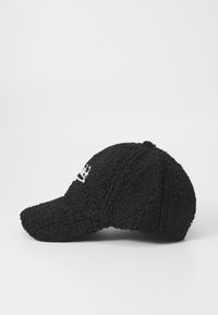 Black cap made of textured fabric, featuring a curved brim and an embroidered logo on the front. The design is structured and fitted.