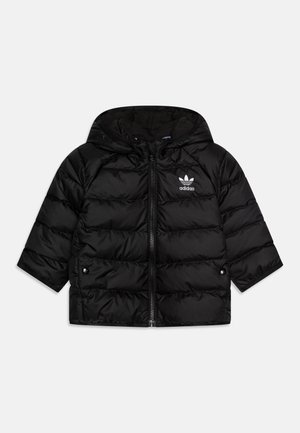 Fekete puffermellény kapucnival, rövid ujjakkal, elülső cipzárral és fehér Adidas logóval a mellkason. Steppelt dizájnja és fényes textúrája jellemzi.